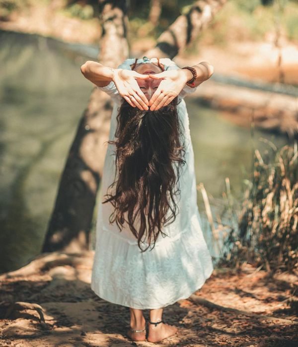Woman performing a calm yoga pose in a dark, serene environment.